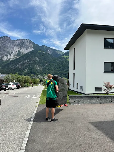Mitarbeiter trägt Möbel, Alpenkulisse